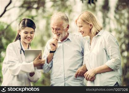 Senior couple man and woman talking to young nurse or caregiver in the park. Mature people healthcare and medical staff service concept.. Senior couple talking to nurse or caregiver.