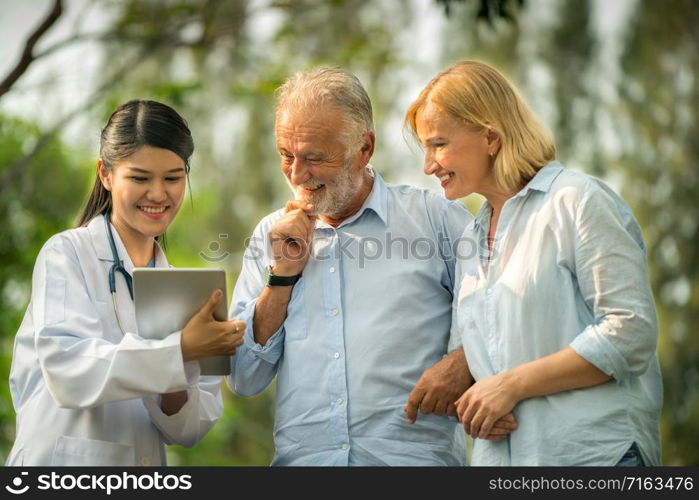 Senior couple man and woman talking to young nurse or caregiver in the park. Mature people healthcare and medical staff service concept.