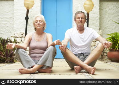 Senior Couple Meditating Outdoors At Health Spa
