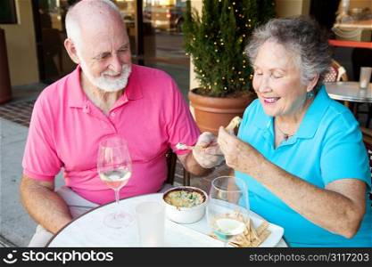 Senior couple on a date enjoys an artichoke dip appetizer.