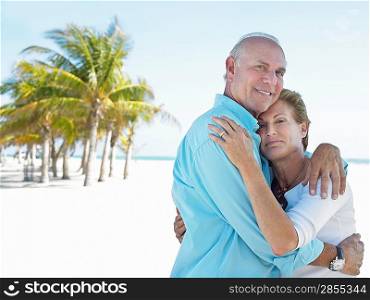 Senior couple on beach embracing on tropical beach