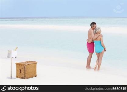 Senior Couple On Beach With Luxury Champagne Picnic