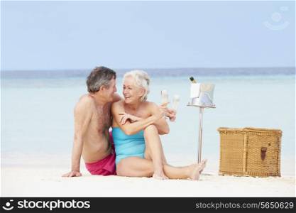 Senior Couple On Beach With Luxury Champagne Picnic