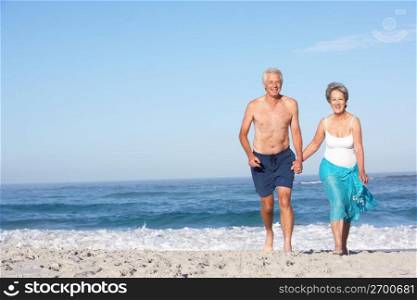 Senior Couple On Holiday Running Along Sandy Beach