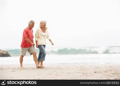 Senior Couple On Holiday Running Along Winter Beach