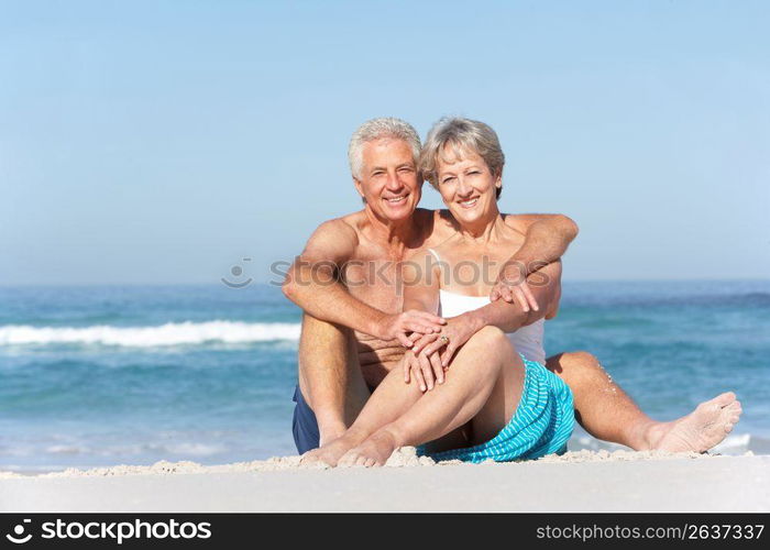 Senior Couple On Holiday Sitting On Sandy Beach