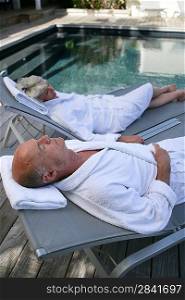 Senior couple on sunloungers by a pool