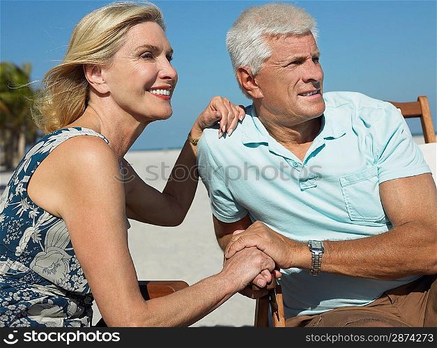 Senior couple on sunloungers on tropical beach close up