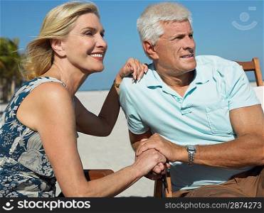 Senior couple on sunloungers on tropical beach close up