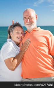 Senior couple on vacation. He&rsquo;s goofing around and giving her rabbit ears.