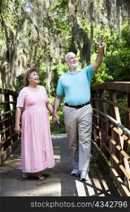 Senior couple on vacation in Florida walking through a tropical park.