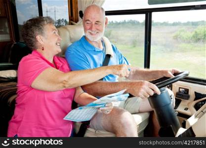Senior couple on vacation in their motor home. The wife is reading the map for the husband.