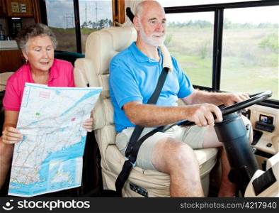 Senior couple on vacation in their motor home. The wife is reading the map to her husband.