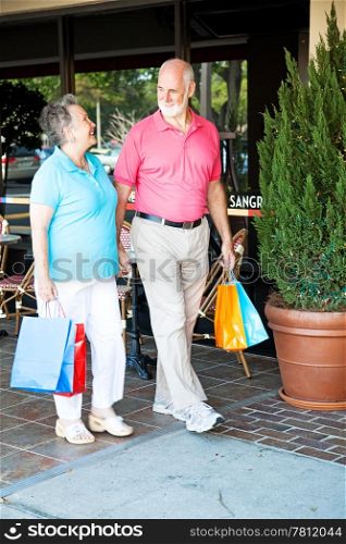 "Senior couple out shopping together. (word visible in window is just "sangria", not restaurant name or logo)"