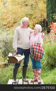 Senior Couple Outdoors With Picnic Basket By Autumn Woodland