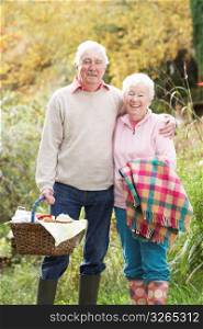 Senior Couple Outdoors With Picnic Basket By Autumn Woodland