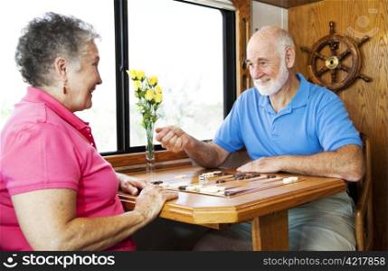 Senior couple playing backgammon in the kitchen of their motor home.