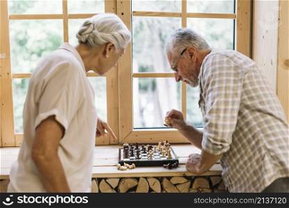 senior couple playing chess window sill