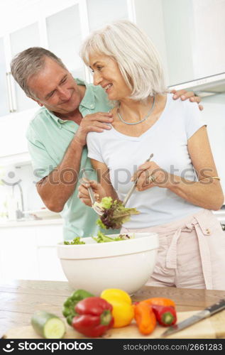 Senior Couple Preparing Salad In Modern Kitchen