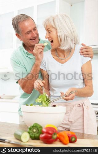 Senior Couple Preparing Salad In Modern Kitchen