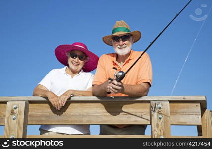 Senior couple protects themselves from the sun while fishing, using hats and sunglasses.