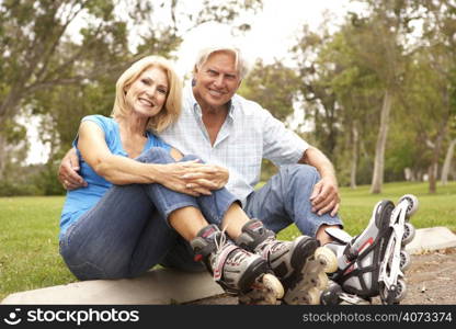 Senior Couple Putting On In Line Skates In Park