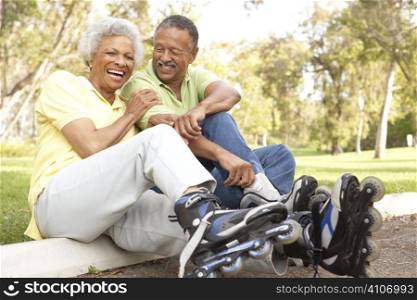 Senior Couple Putting On In Line Skates In Park