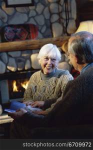 Senior couple reading in front of a fireplace