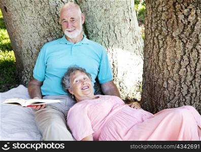 Senior couple reading together outdoors in the park.