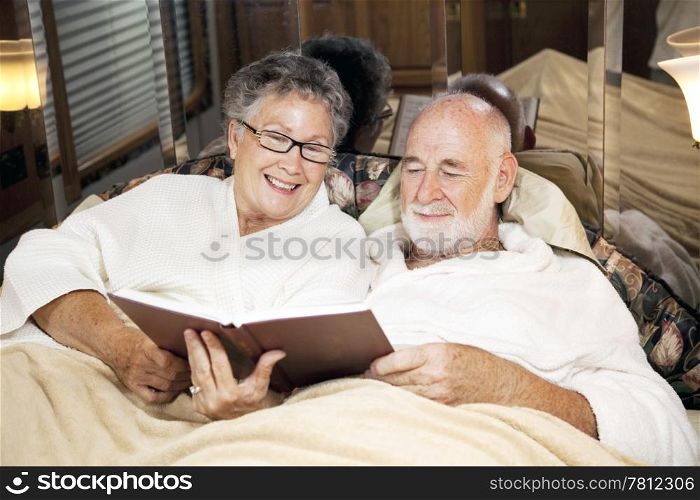 Senior couple reads together at bedtime, in their motor home.