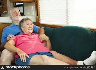 Senior couple relaxes and watches TV on the couch in their motor home.