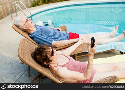 Senior couple relaxing by swimming pool