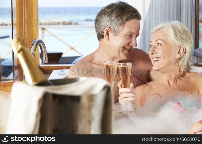 Senior Couple Relaxing In Bath Drinking Champagne Together