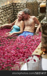 Senior Couple Relaxing In Flower Petal Covered Pool At Spa