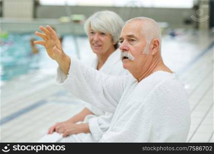 senior couple relaxing in swimming pool together