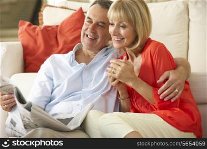 Senior Couple Relaxing On Sofa At Home Reading Newspaper