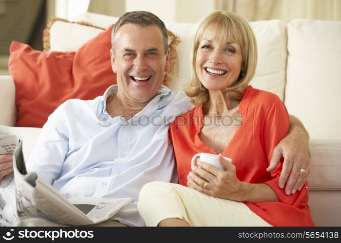 Senior Couple Relaxing On Sofa At Home Reading Newspaper