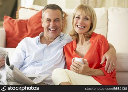 Senior Couple Relaxing On Sofa At Home Reading Newspaper