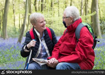 Senior Couple Resting On Walk Through Bluebell Wood