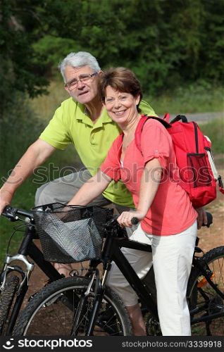 Senior couple riding bicycle in countryside