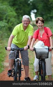 Senior couple riding bicycle in countryside