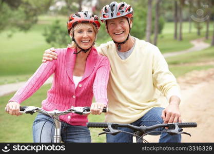 Senior couple riding bicycle in park