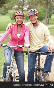 Senior couple riding bicycle in park