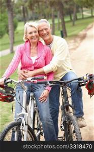 Senior couple riding bicycle in park