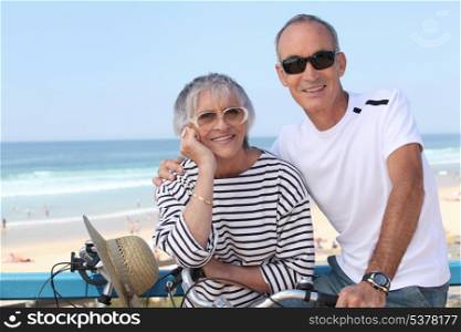 Senior couple riding bikes by the beach