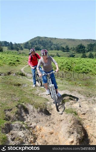 Senior couple riding mountain bikes in natural landscape