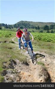 Senior couple riding mountain bikes in natural landscape