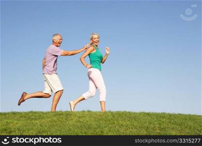 Senior couple running though field