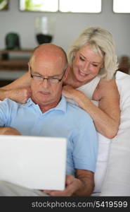 Senior couple sat on the sofa surfing the internet