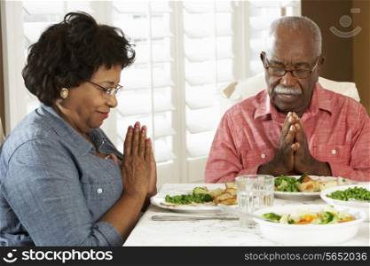 Senior Couple Saying Grace Before Meal At Home
